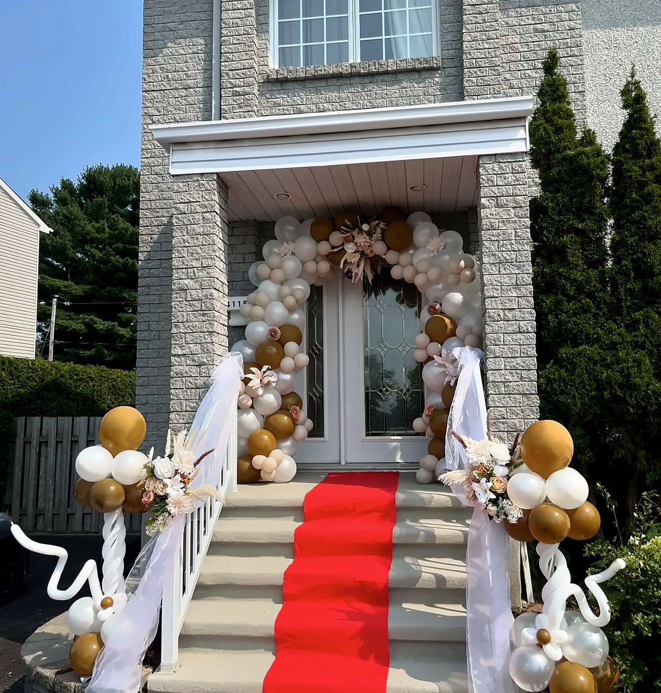 Entrée décorée d’une arche de ballons dorés et d’un tapis rouge