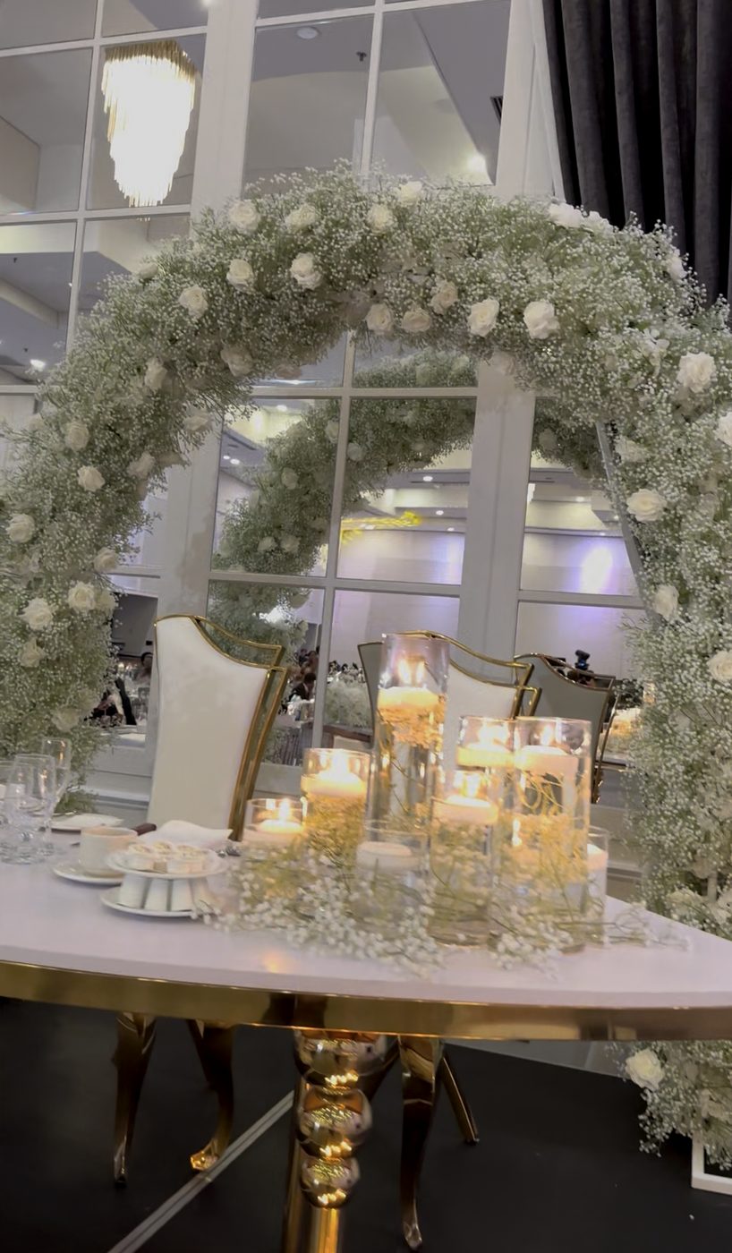 Bougies flottantes et gypsophile sur une table d’honneur dorée