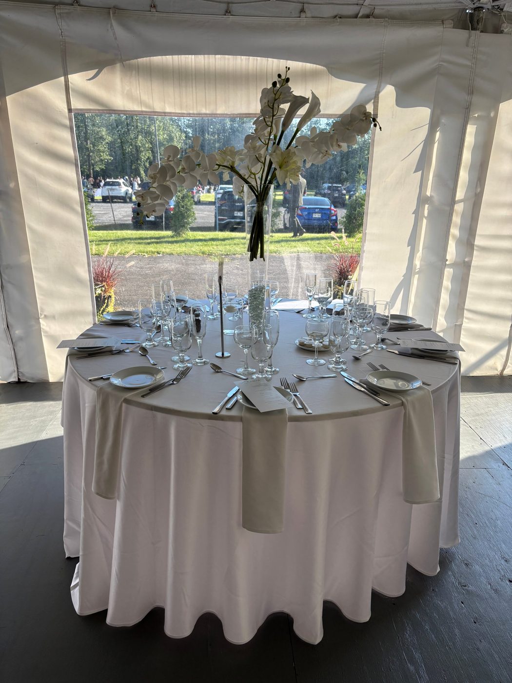 Table de mariage sous chapiteau, centre d’orchidées blanches